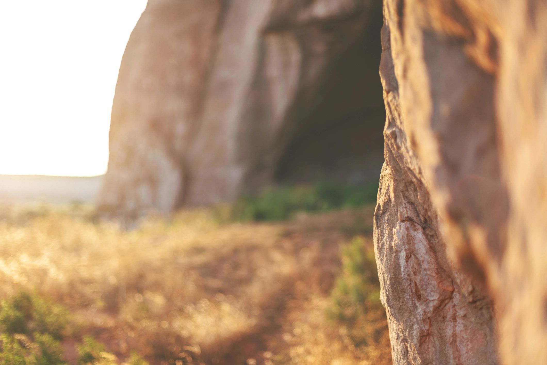 Sandstone outcropping with cave-like opening in an arid landscape.