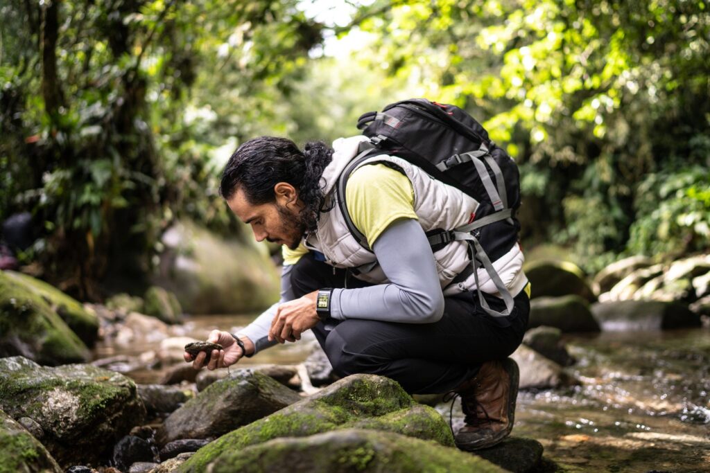 Man admiring a rock during hiking in a forest